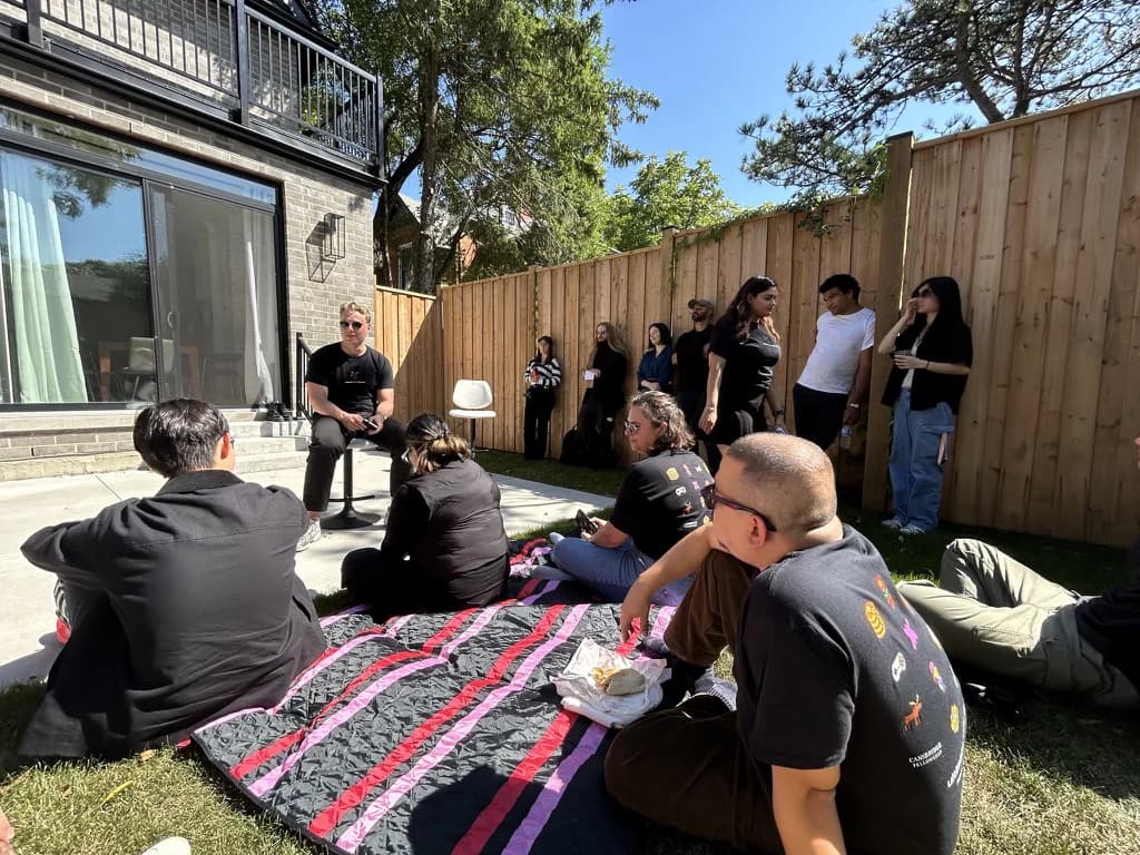 People sitting on blankets during a backyard community picnic.